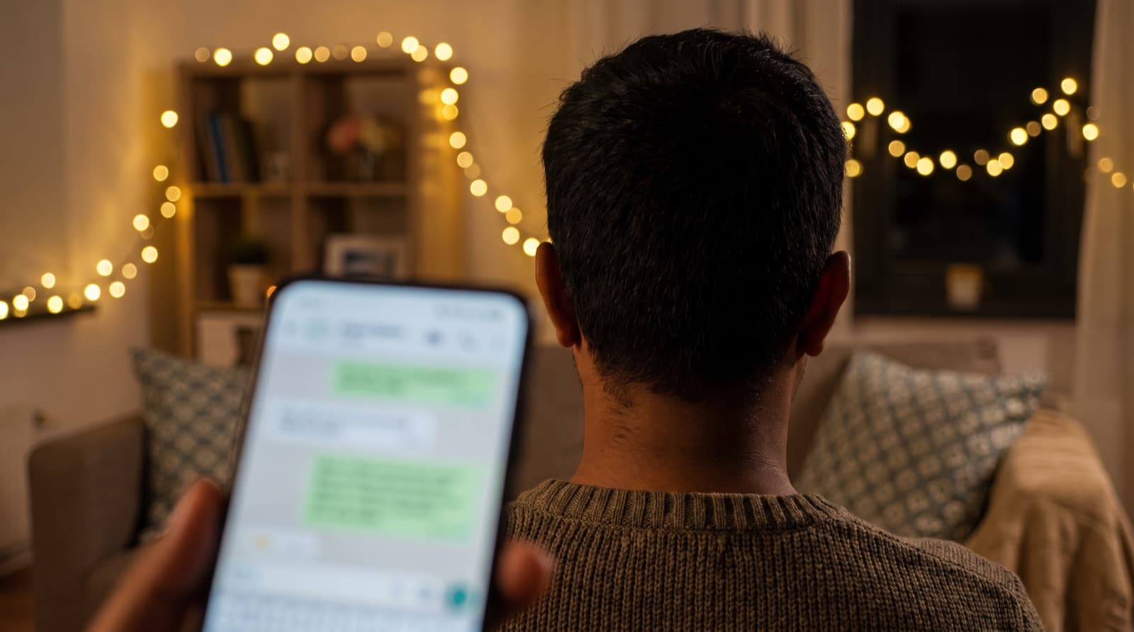 Raat mein fairy lights wale kamre mein phone par chat karta hua ladka