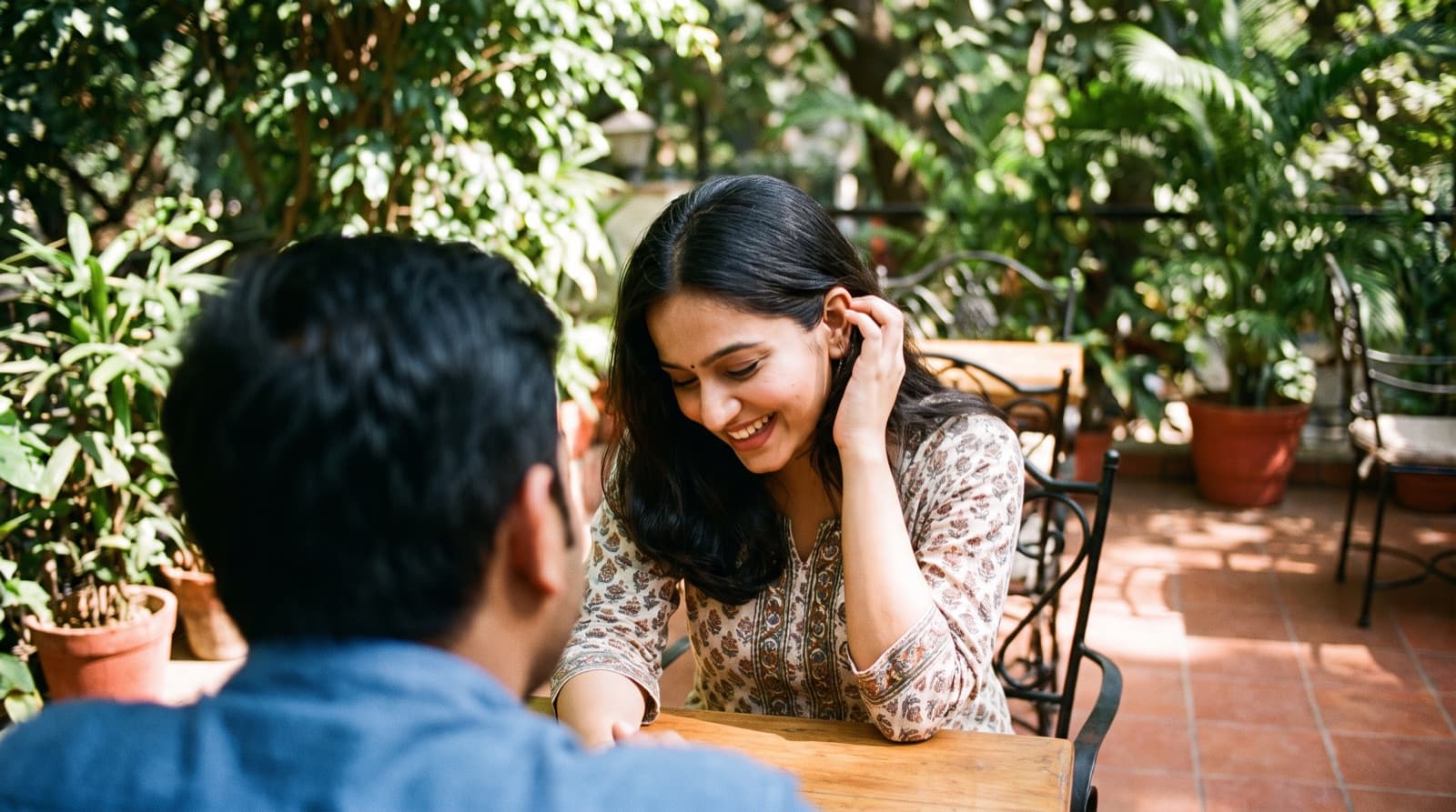 A woman laughing shyly at a compliment in a cafe